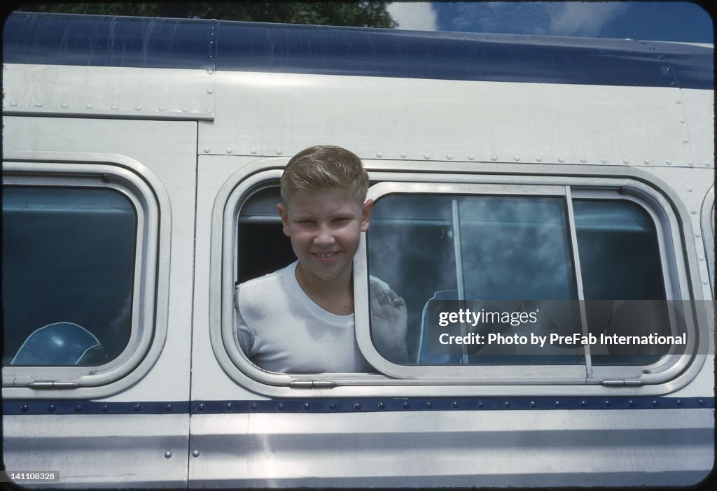 Boy leans out of open bus window