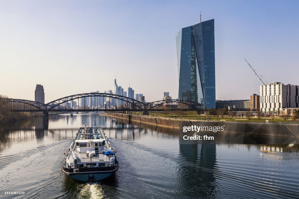 Frankfurt/ Main skyline and ECB building with freight ship (Hesse, Germany)