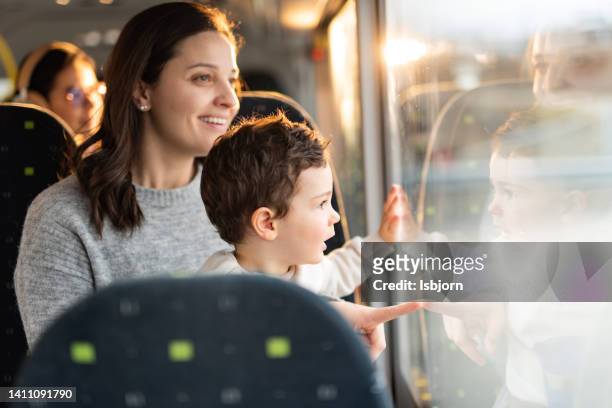 mother and son on a bus looking out of the window - getting on bus stockfoto's en -beelden
