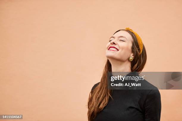 smiling young woman standing in front of orange wall - portrait orange background stock pictures, royalty-free photos & images