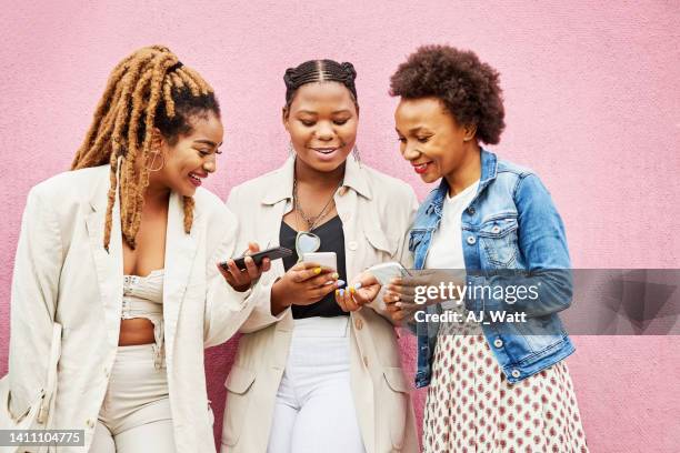 three stylish women using their mobile phones and smiling - natural black hair stock pictures, royalty-free photos & images