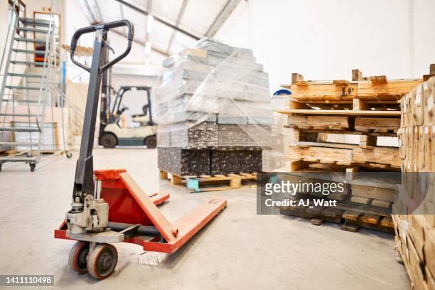 pallet jack and boxes on the floor of a large warehouse - pallet jack stock pictures, royalty-free photos & images