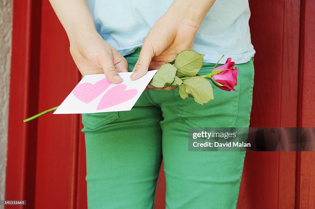 Guy with a love letter & rose outside a red door