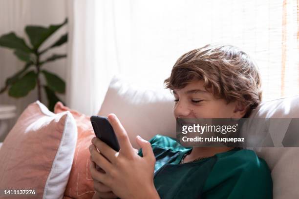 teenager boy with smart phone at living room - fair haired boy stockfoto's en -beelden