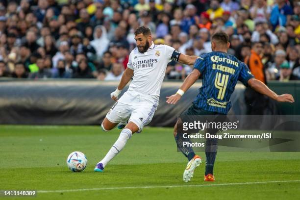 Karim Benzema of Real Madrid takes a shot and scores a goal while defended by Sebastian Caceres of Club America during a game between Club America...