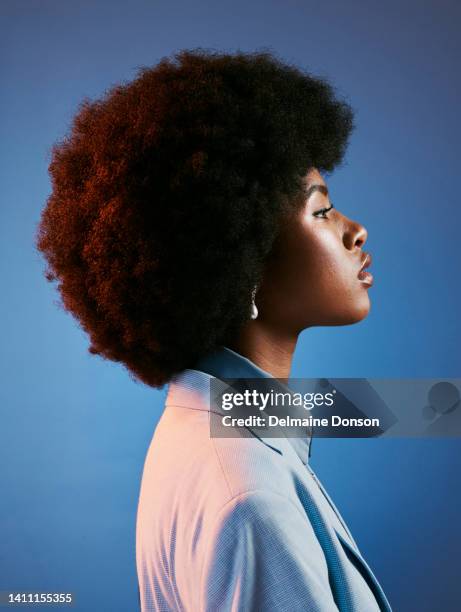 profil des wilden, afro- und retro-modells mit haltung, perfekter haut und einer coolen, funky und trendigen frisur. ein kraftvolles porträt einer intensiven, stolzen und modischen frau vor blauem studiohintergrund - woman portrait skin stock-fotos und bilder