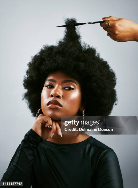 portrait of a beautiful african lady with an afro looking at the camera. confident female with curly hair proud of her hairstyle. trendy black woman getting her hair cut by hair stylist - afro stockfoto's en -beelden