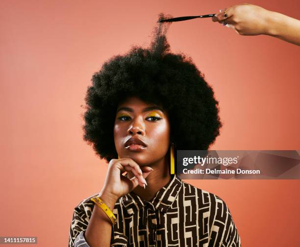 portrait d’une jeune femme noire élégante se faisant coiffer sur un fond de studio orange seule. femme confiante et tendance avec un afro à l’air puissant tout en faisant des soins capillaires - love woman photos et images de collection