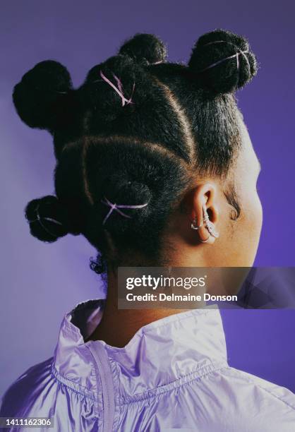 headshot of 90s retro woman with knots hairstyle to inspire your next look. edgy and funky girl feeling confident in purple fashion against studio background. african female with a stylish hairdo - look back stockfoto's en -beelden