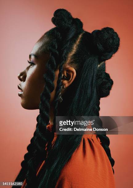 edgy young black woman with trendy braided hairstyle against an orange studio background. profile of a confident, serious and stylish african american female with bold personality and cool attitude - flätor bildbanksfoton och bilder