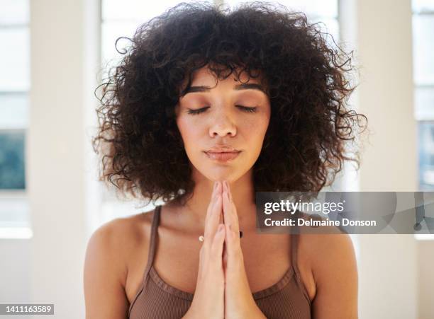 una mujer tranquila y espiritual que se siente pacífica mientras practica anjali mudra, namaste, manos de oración con palmas juntas dentro de una habitación luminosa. mujer joven haciendo yoga gesto de saludo o meditación. - prayer pose greeting fotografías e imágenes de stock