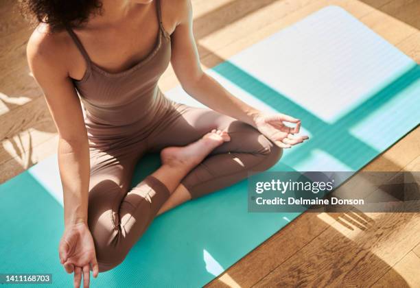 fitness woman meditating and practicing yoga while sitting in lotus pose on an exercise mat at home. young female finding her center, inner peace and balance. being mindful on her journey to zen - upright position stock pictures, royalty-free photos & images