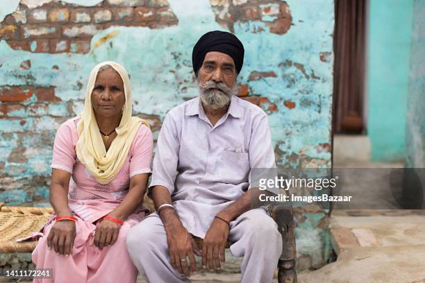 portrait of a senior sikh couple sitting on charpoy at home - charpoy stock pictures, royalty-free photos & images