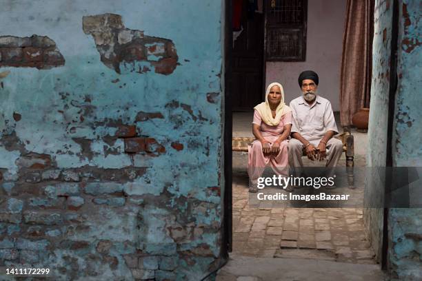 portrait of a senior sikh couple sitting on charpoy at home - charpoy stock pictures, royalty-free photos & images