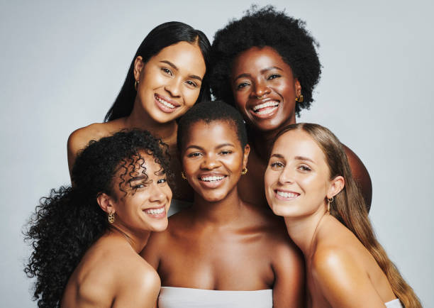 beauty portrait of a diverse group of beautiful women smiling together against a grey studio background. faces of female models with perfect, clear skin and complexion from a daily skincare routine - mulher bonita imagens e fotografias de stock