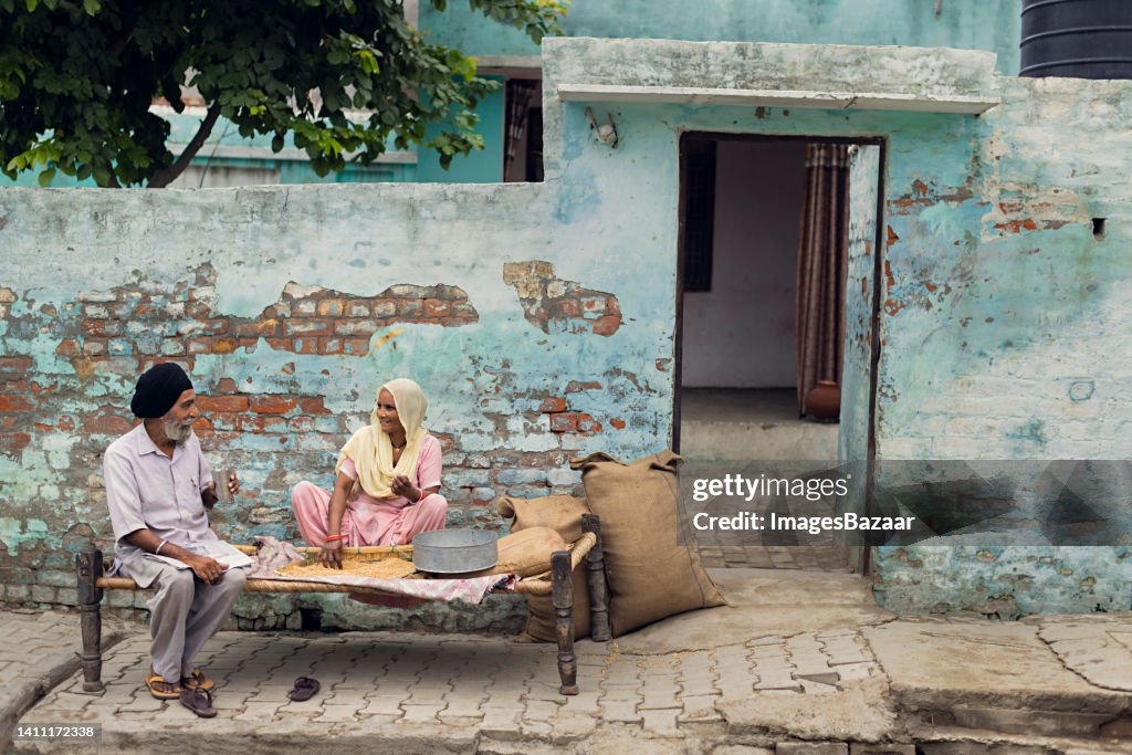Senior Sikh couple sitting on charpoy at home