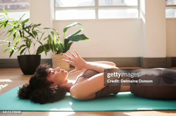 an active and mindful woman meditating in her house as part of her morning exercise routine. a fit female doing yoga at home training her balance and body strength. an athletic lady doing a workout - ligga ner bildbanksfoton och bilder