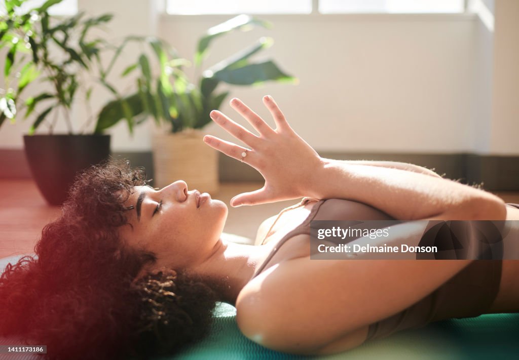 African American woman lying down in prayer pose. Daily yoga improves mindfulness and mental clarity. Spirituality and exercise combined bring about wellness for body and soul.