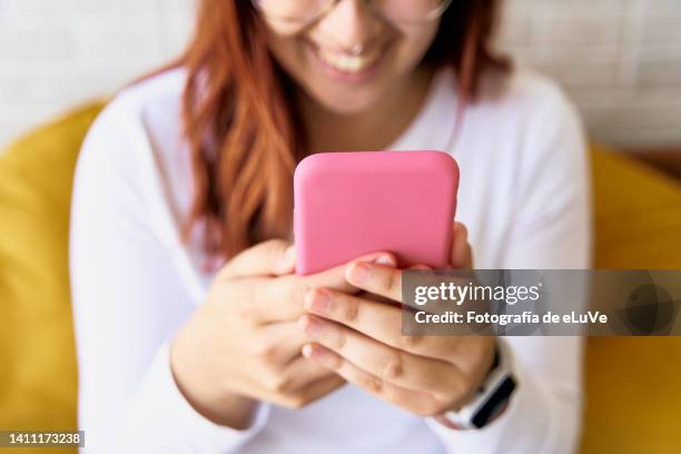 irreconocible teenager girl texting in social networks by internet with a smile with a cell phone - filipino girl stockfoto's en -beelden