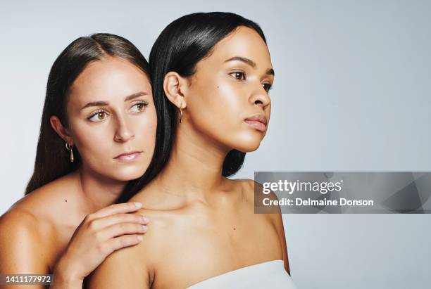 duas mulheres impecáveis com pele brilhante isoladas no fundo do estúdio. rosto de modelos de beleza multicultural parecendo confiantes e empoderados por sua rotina de skincare natural, limpa e hidratada - clavicle - fotografias e filmes do acervo