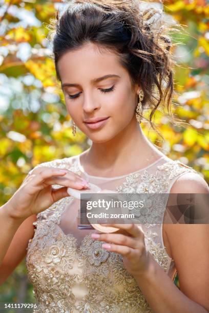 schöne junge brünette in champagnerfarbenem spitzenkleid mit kompaktem puder - spitzenkleid stock-fotos und bilder