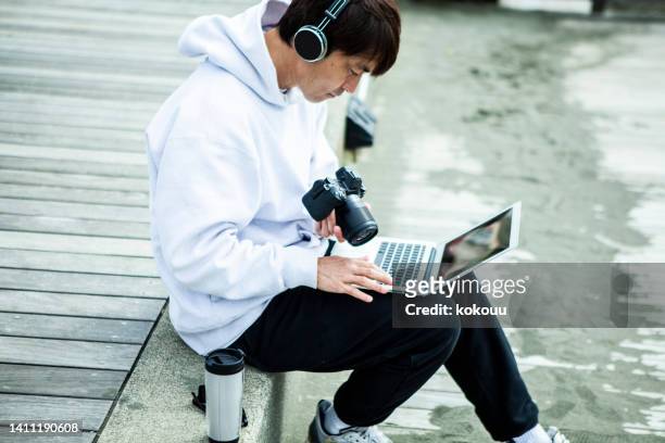 male video creator is working at the beach. - creative director stock pictures, royalty-free photos & images