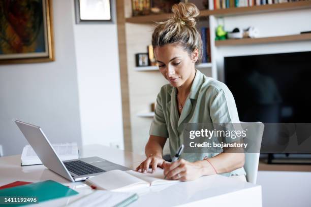 beautiful young woman taking notes while learning from home - översättning bildbanksfoton och bilder