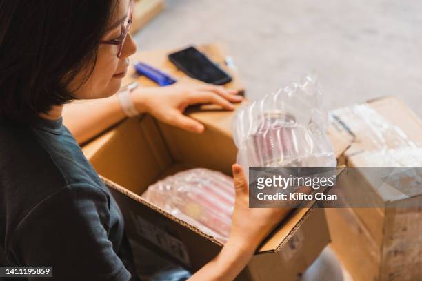 over the shoulder view of asian woman unpack the package she ordered online - packaging stock-fotos und bilder