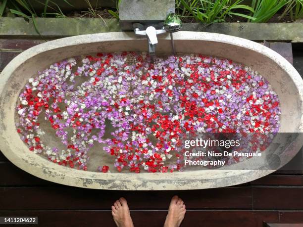 man standing in front of bathtub full of flowers, bali, indonesia - bali spa stock pictures, royalty-free photos & images