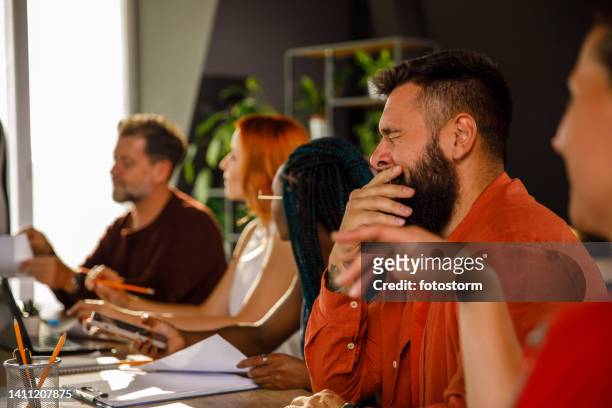 müder geschäftsmann, der in einer besprechung mit kollegen sitzt und gähnt - yawn office stock-fotos und bilder