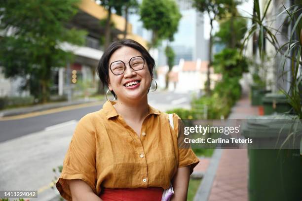 portrait of a happy woman on the way home - chinese woman outside walking stock-fotos und bilder