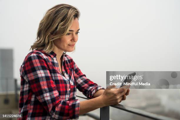 mid shot portrait of young woman conducting personal finances from her cell phone - etf stock pictures, royalty-free photos & images