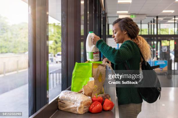 empacar comestibles en un supermercado - frugalidad fotografías e imágenes de stock