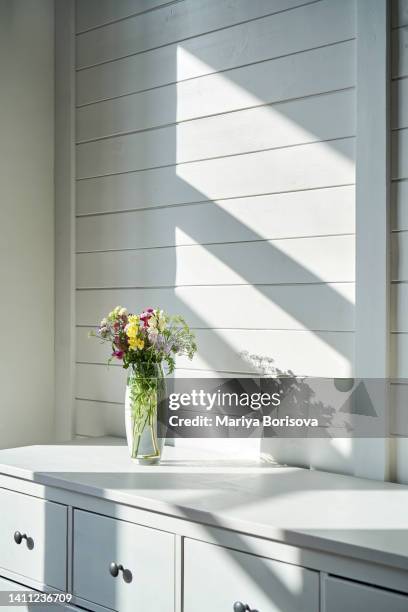 a glass vase with flowers on a white wooden wall background. simple home comfort. - flowers vase ストックフォトと画像