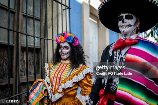 couple walking and celebrating the day of the dead outdoors - dia de los muertos dresses stock pictures, royalty-free photos & images
