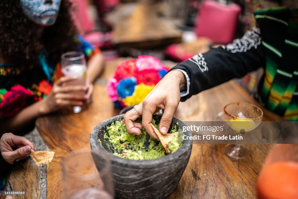 People eating guacamole with nachos on the day of the dead at bar