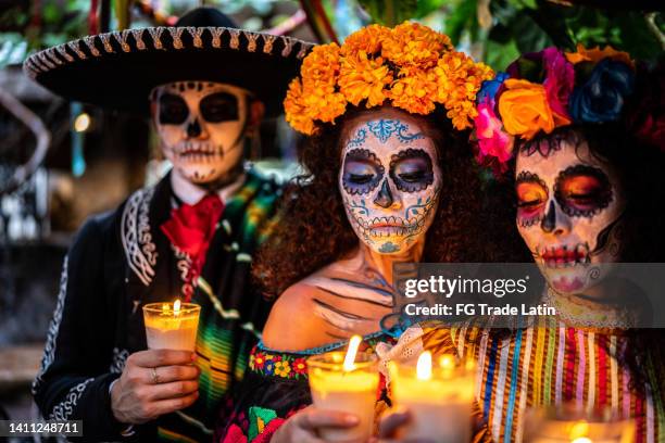 amigos celebrando el día de muertos encendiendo vela - all souls day fotografías e imágenes de stock