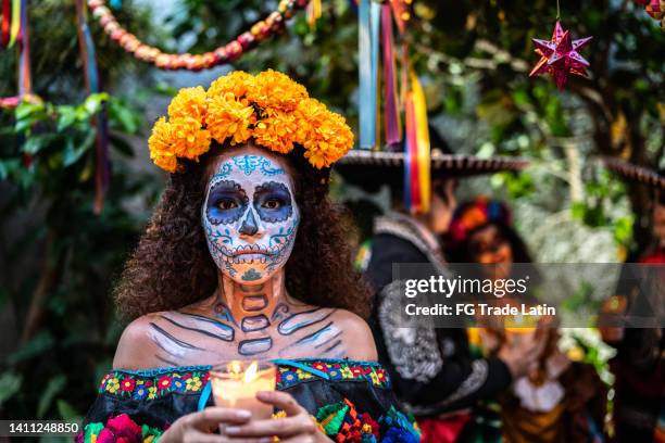 porträt einer jungen frau, die den tag der toten feiert, der die kerze anzündet - la catrina stock-fotos und bilder