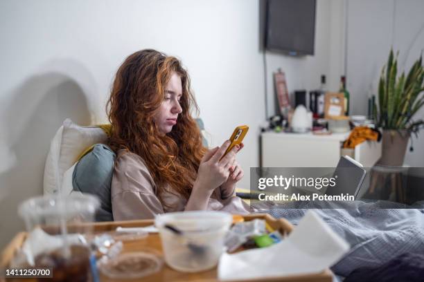 internet and gadget addiction. wasting time on smartphone. woman lying in bed with phone and empty plastic containers. focus on background with defocused foreground. - alex potemkin coronavirus stock pictures, royalty-free photos & images