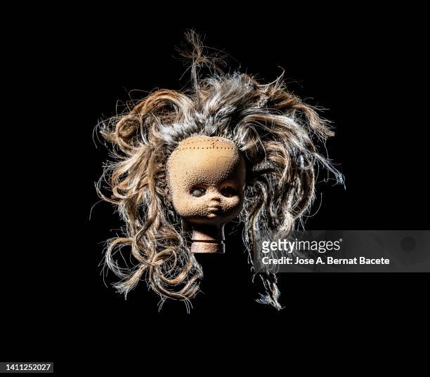 head of an old broken doll with blonde hair, torn and weathered by fire, on a black background. - ugly face stock pictures, royalty-free photos & images