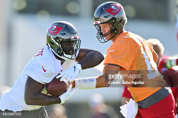 Tom Brady of the Tampa Bay Buccaneers hands the ball off to Leonard Fournette during Buccaneers Training Camp at AdventHealth Training Center on July...