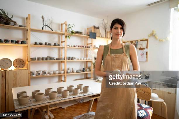 portrait of young caucasian woman in her pottery workshop - artist portrait stock pictures, royalty-free photos & images