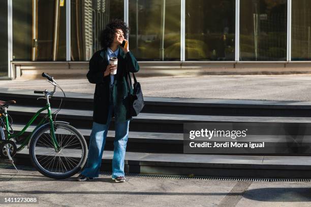 woman enjoying a cup of coffee and talking on the phone in the financial district. - coffee bike stock pictures, royalty-free photos & images