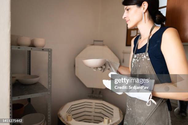 young woman in her pottery workshop - kiln stock pictures, royalty-free photos & images