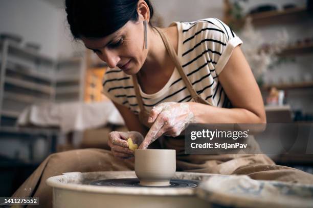 femme moulant un pot en argile avec une éponge - pottery wheel photos et images de collection