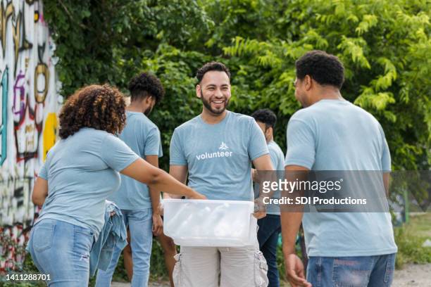 young adult male volunteer hands out supplies - cleaning graffiti stock pictures, royalty-free photos & images