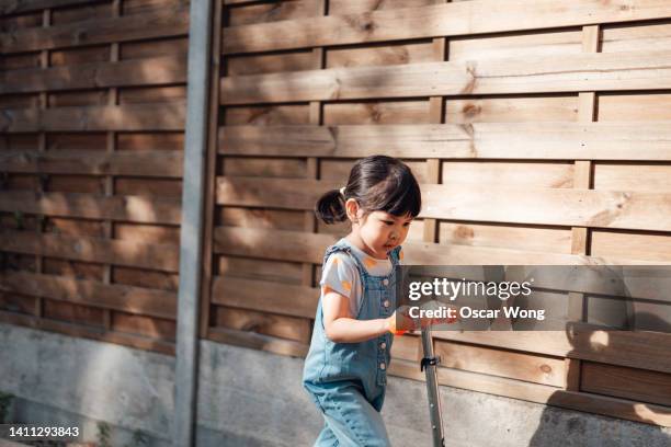 young asian girl riding scooter at the backyard - girl riding scooter stock pictures, royalty-free photos & images