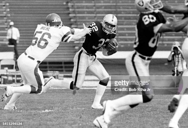 Raiders RB Marcus Allen straight arms New York Jets LB Lance Mehl during AFC Playoff game, January 15, 1983 in Los Angeles, California.