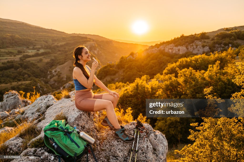 Young Woman Having A Snack On The Mountain After A Hike