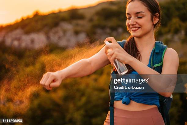 young woman applying mosquito repellent on the top of the mountain - insect spray stock pictures, royalty-free photos & images